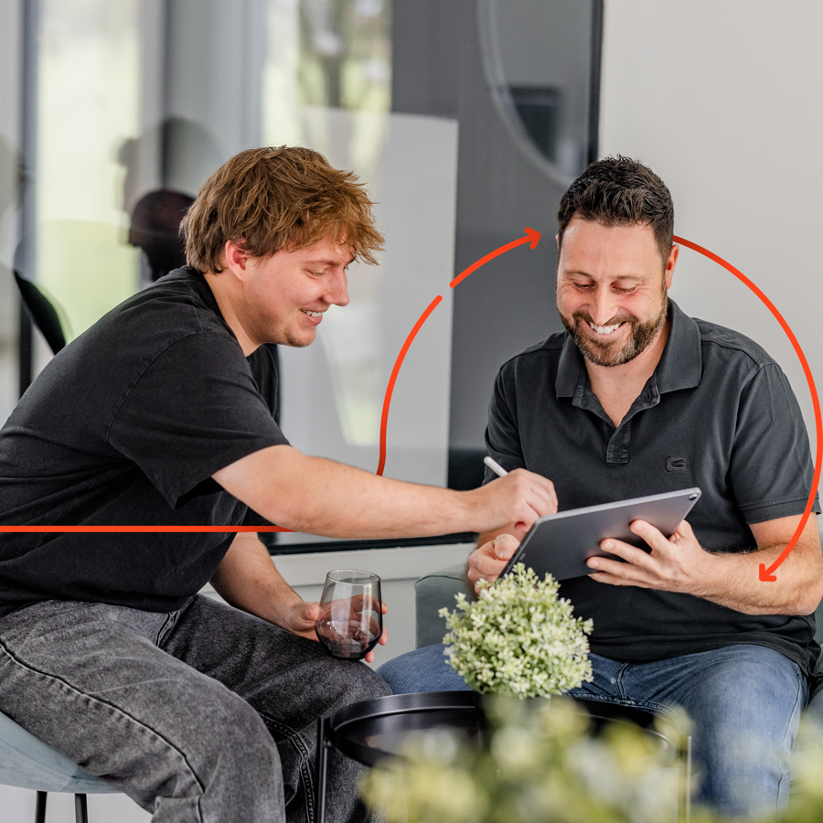 Zwei Kollegen besprechen ein Projekt an einem Tablet in einem modernen Büro – Zusammenarbeit und Teamwork bei NoMa Tech Consulting.